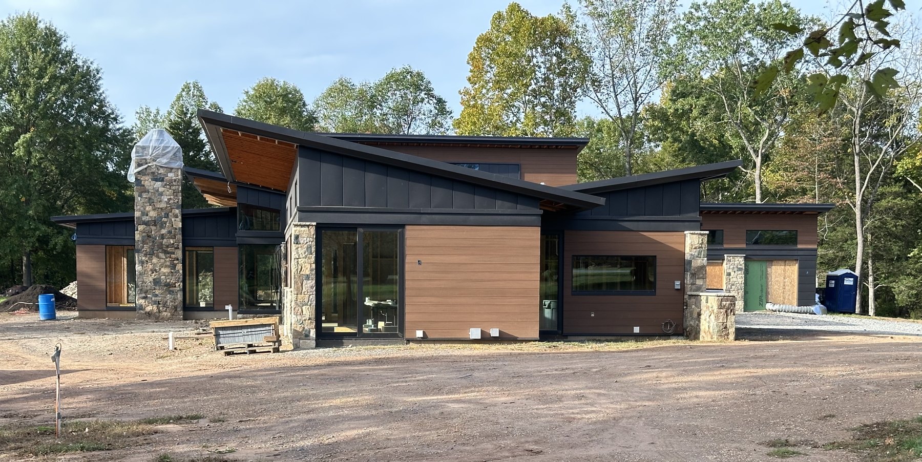 Haymarket — modern home with shed rooflines, wood, stone, and dark metal cladding
