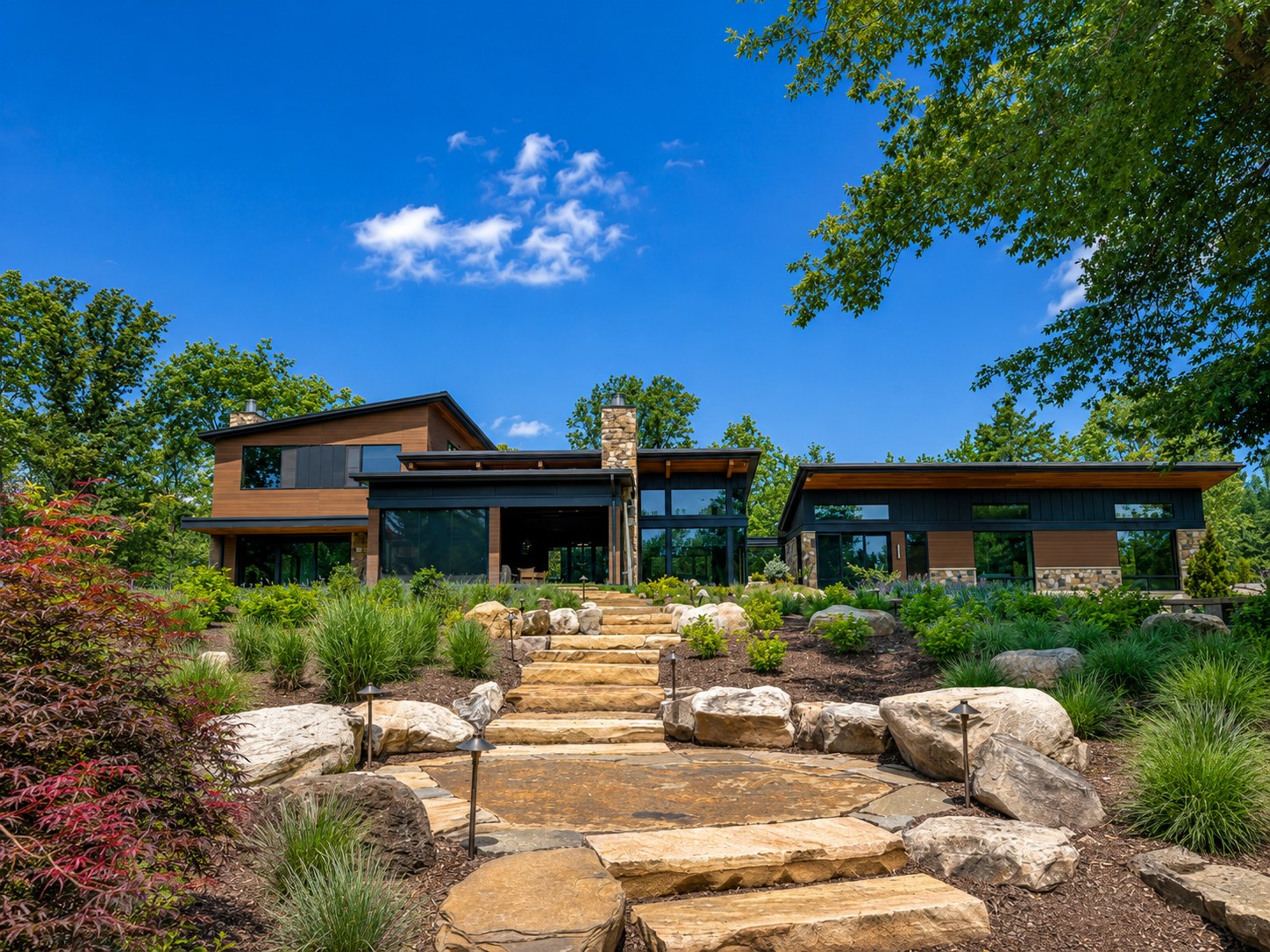 Haymarket nearing completion — the same garden elevation finished in stone, warm wood, and dark metal with landscaped stone steps