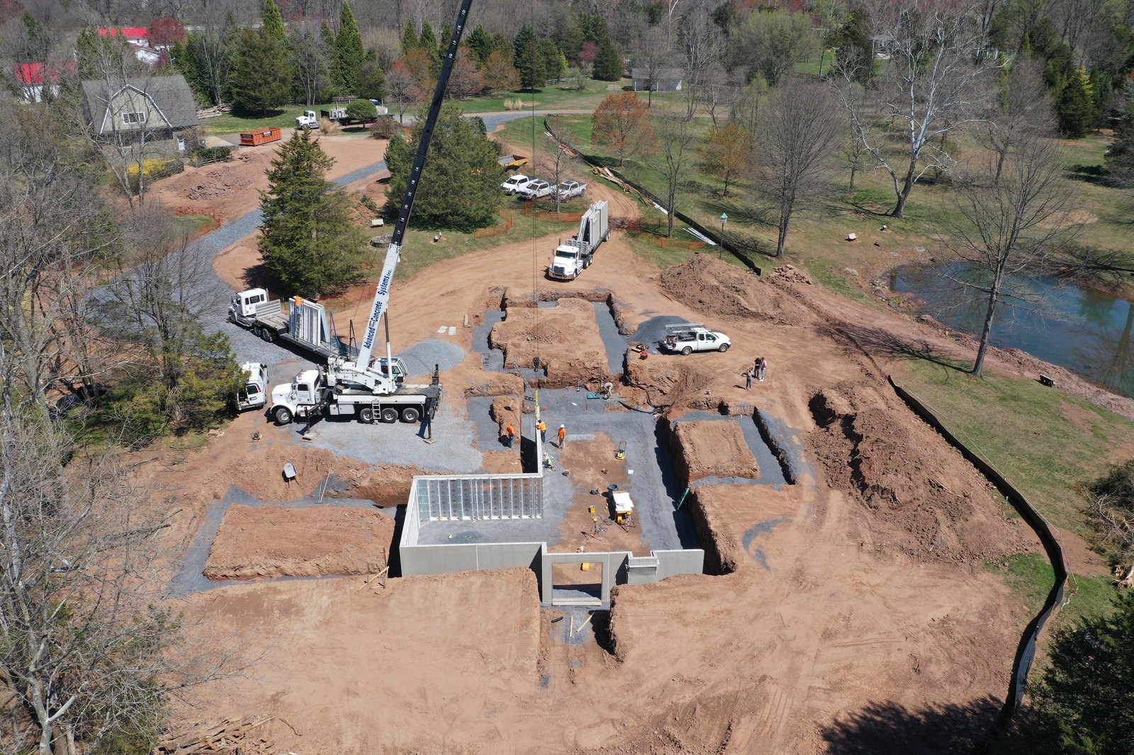 Aerial view of the Haymarket site — concrete foundations set into the cleared lot with a pond beyond